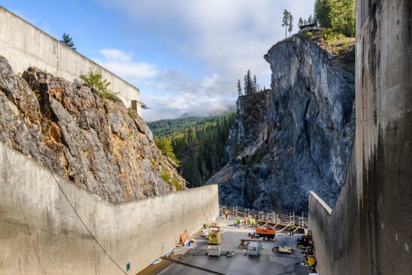 Boundary Dam with blue sky workers on spillway with trees in background