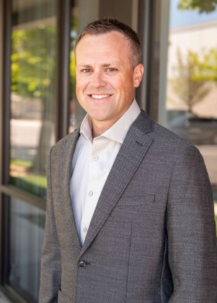 Brett Himes Mountain States & Southwest Top Young Professionals - IMCO Construction Man in suit standing in front of business office