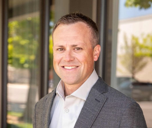 Brett Himes - IMCO Construction man in grey suit standing outside of IMCO building in Boise