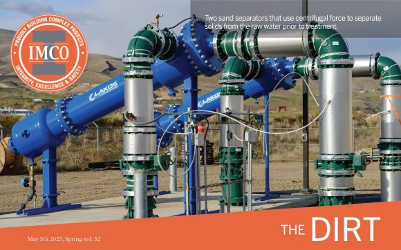 Grey and green piping structure with dirt hills in background