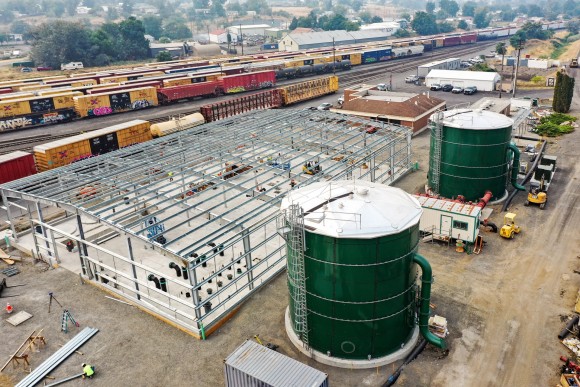 Lewiston Water Treatment Plant - IMCO Construction Two large green round metal tanks in front of steel framing and train cars