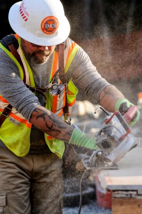 Construction worker in hard hat operating a saw