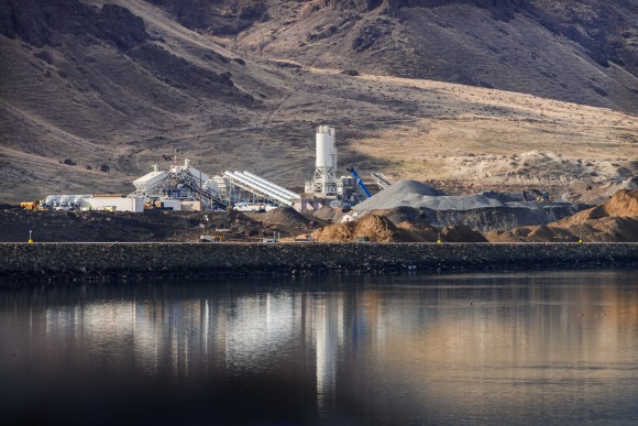 white batch plant with water and brown hills in background