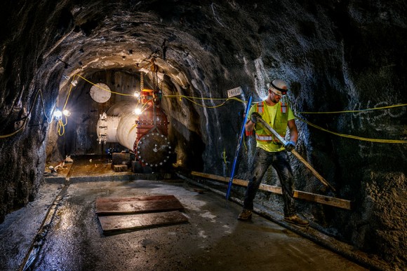 Culmback Dam Tunneling Project IMCO Construction Photo construction worker with hard hat standing in tunnel with lights