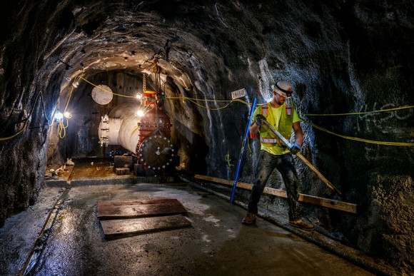 construction worker with hard hat standing in tunnel with lights