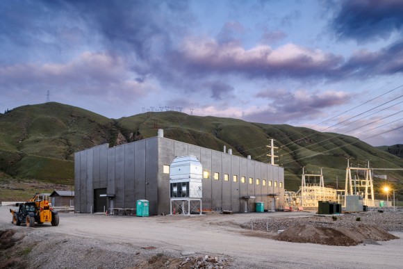 Hydrogen Production and Fueling Facility - IMCO Construction Concrete building sitting in front of green hills, power lines and construction equipment.