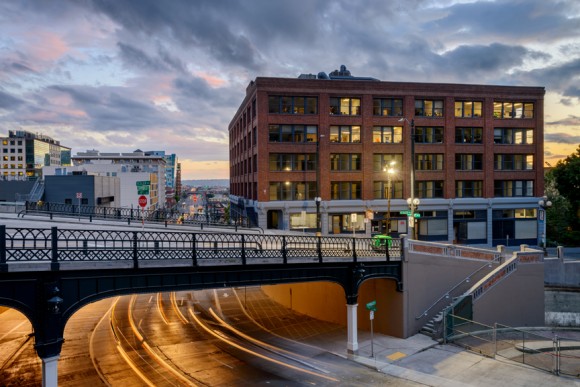 Yesler bridge and Seattle roadway with cloudy sunset sky and brick building in background 