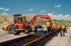 Excavator, bulldozer, and construction crew working on railroad