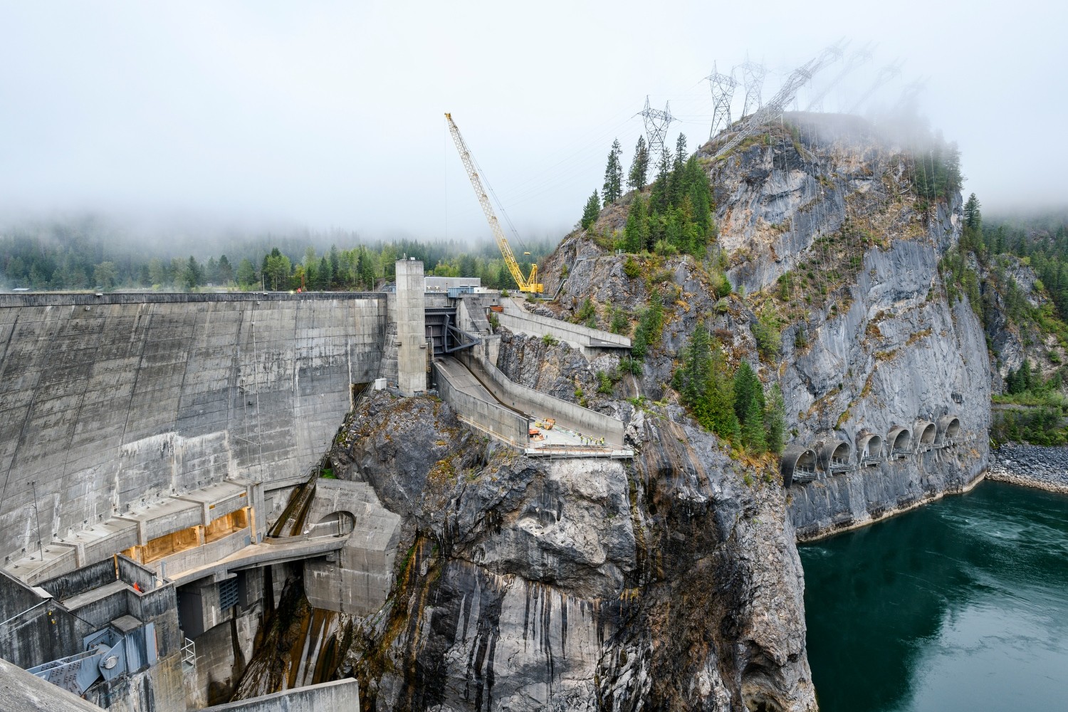 Boundary dam spillway with crane, dramatic landscape, and river