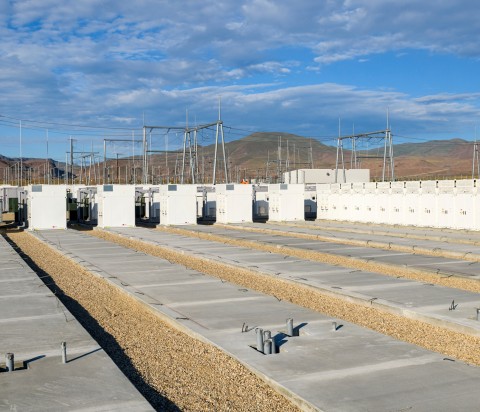 concrete pads with white energy storage batteries placed on top with mountains in background