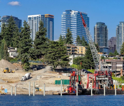 Meydenbauer Bay Park with crane on barge and heavy equipment along shoreline, City of Bellevue buildings skyscape