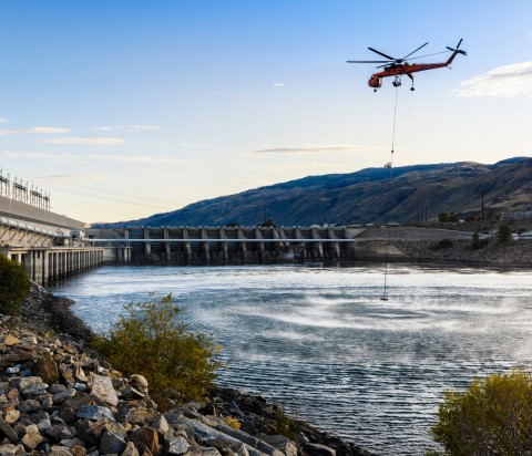 Helicopter placing a new buoy system at the base of dam