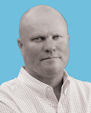 Headshot of man with blue background.