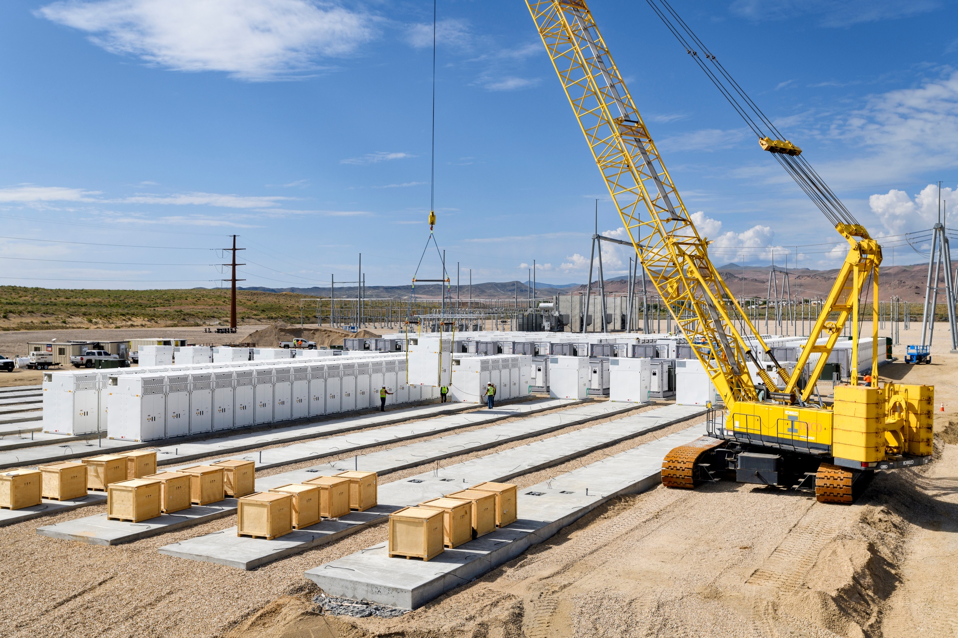 concrete battery pads and yellow crane picking equipment at battery storage facility