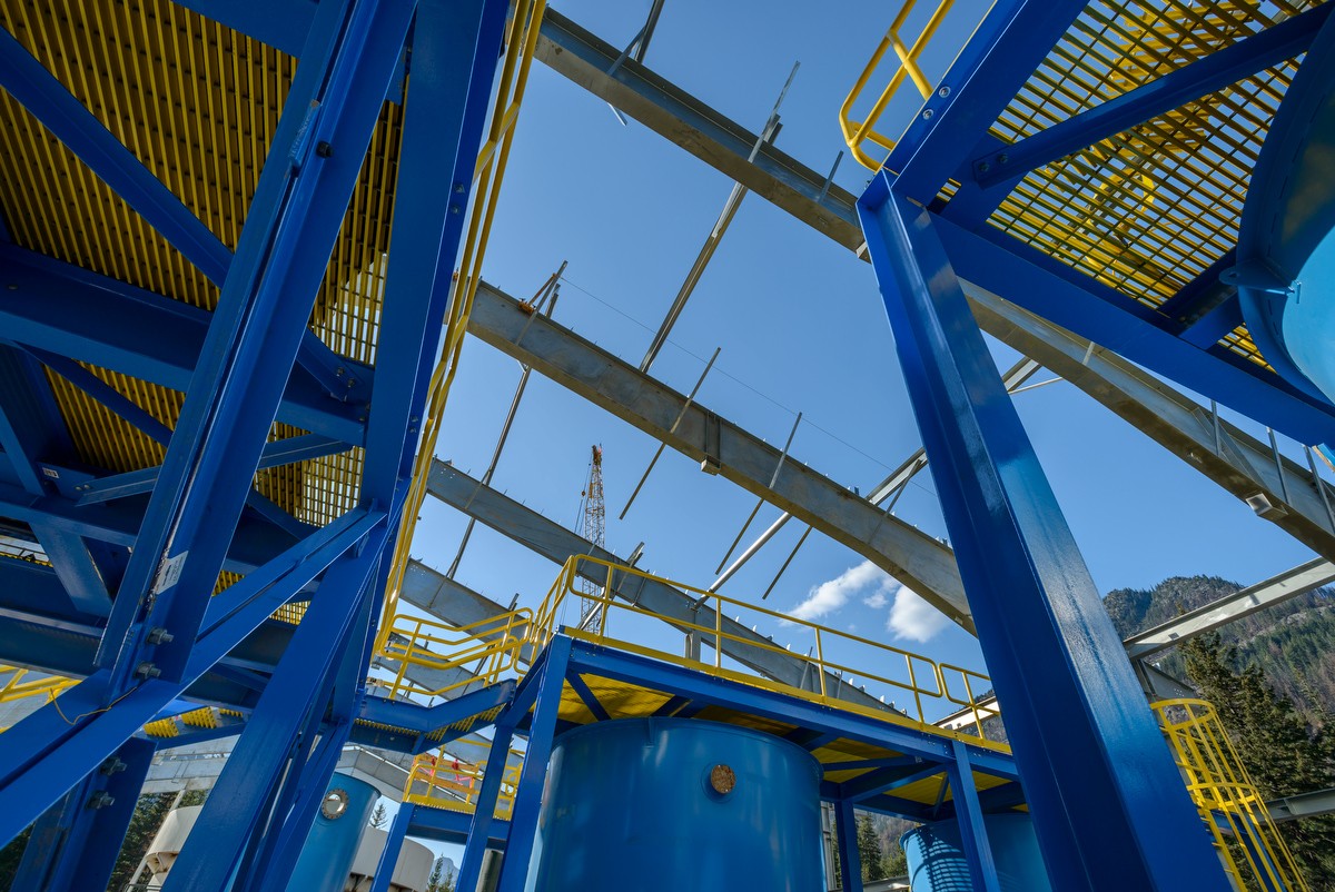 Looking up through blue steel structure with crane peeking through