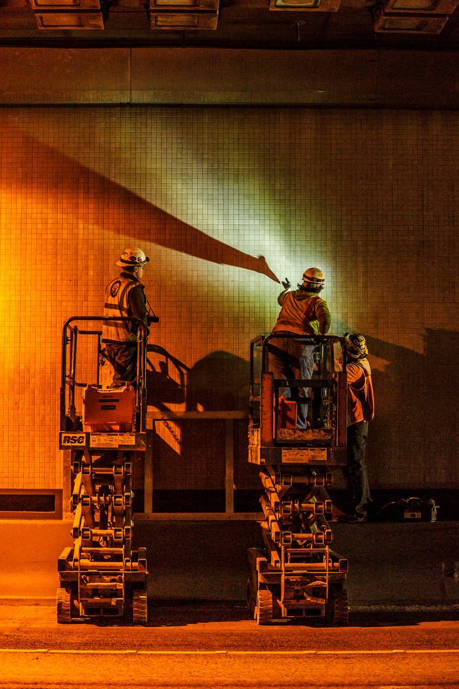 Two men working on lift inside tunnel