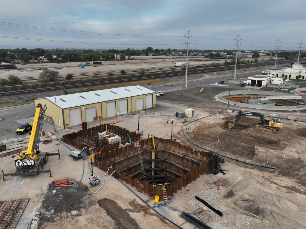 deep square shaped holes in the ground next to a yellow crane and outbuilding