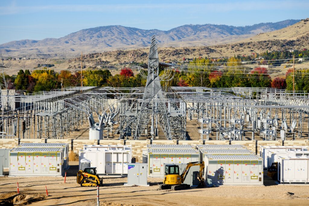 large white boxes under multiple electrical lines and construction vehicles on jobsite