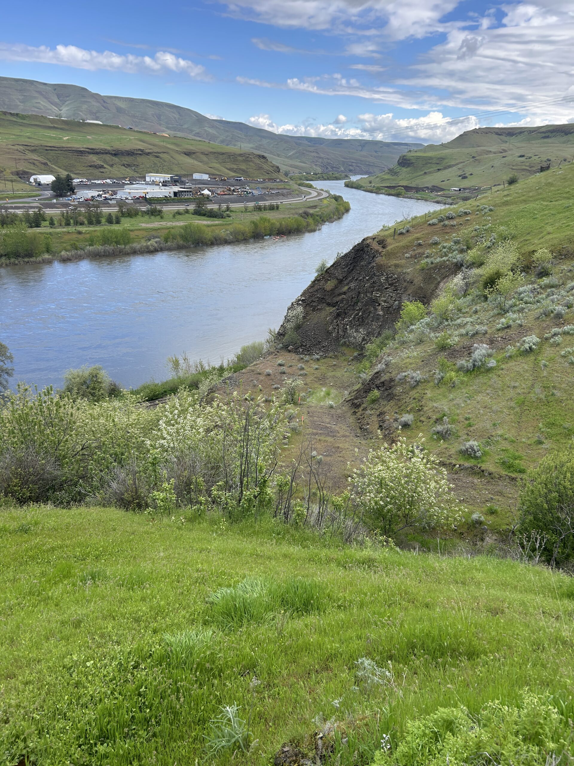 River winding through green hills beneath a partly cloudy sky.