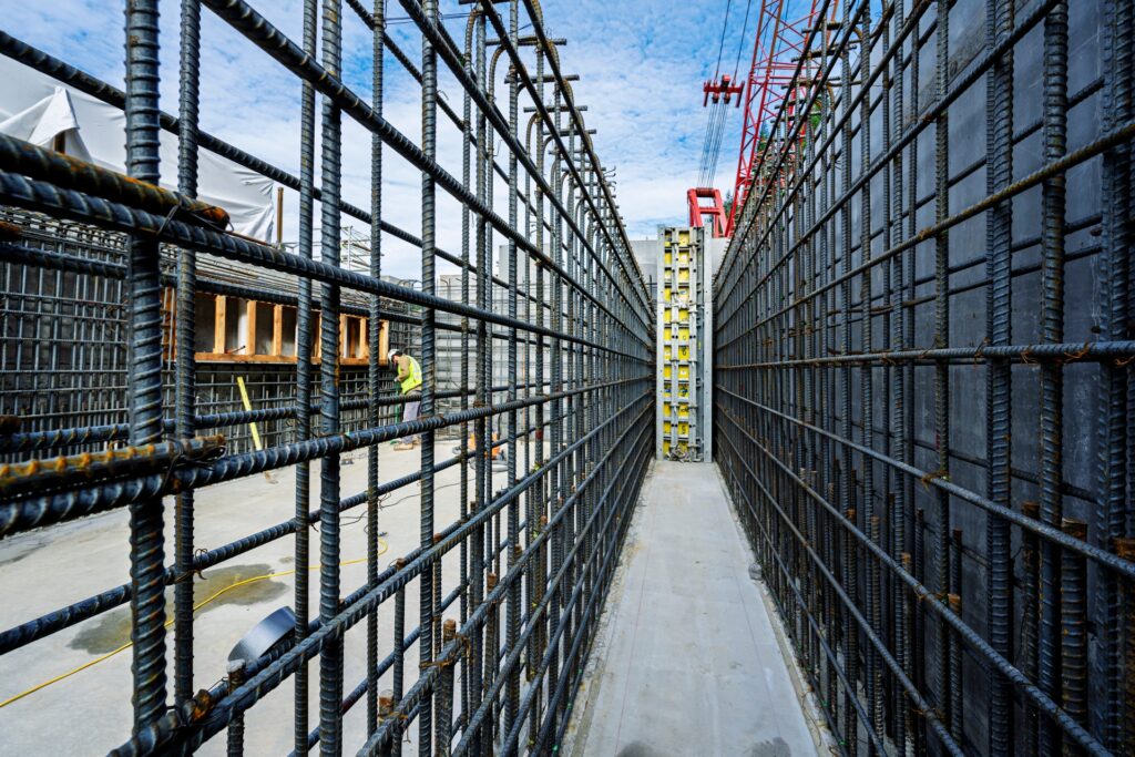 construction site with rebar wall and crane in background